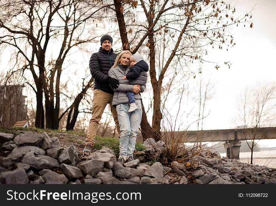 Outdoors portrait of a young family with a little son walking in the autumn park