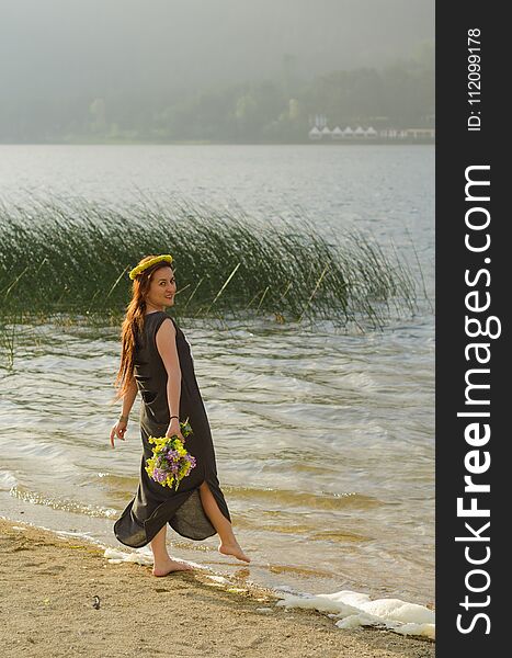 Young woman with yellow flowers in her hand at the lake shore, l