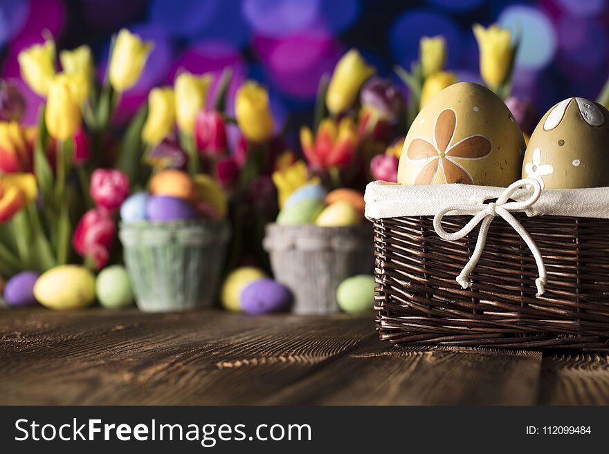 Easter eggs and tulips on wooden rustic table. Blue bokeh background. Easter eggs and tulips on wooden rustic table. Blue bokeh background.