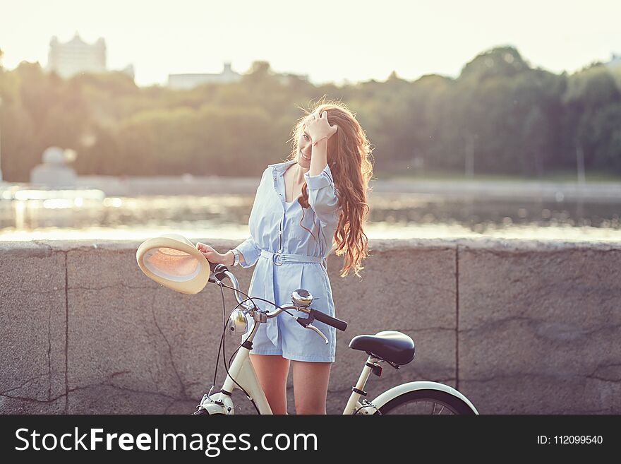 Portrait of a smiling woman with a bicycle at sunset