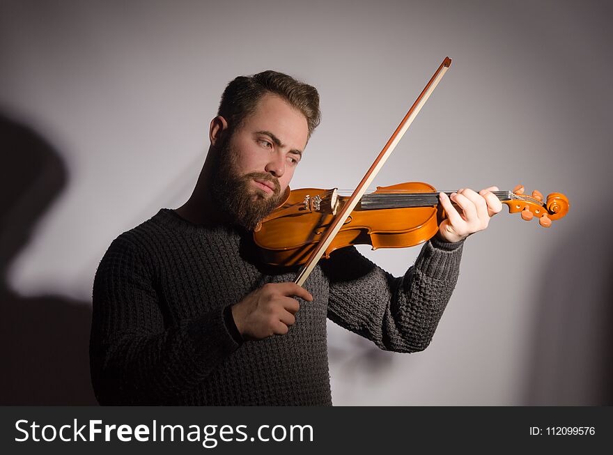 Art and artist. Young emotional man violinist fiddler playing violin. Classical music. in studio shot.
