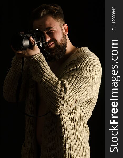 Young model posing by photographing in studio, wearing cardigan, bearded
