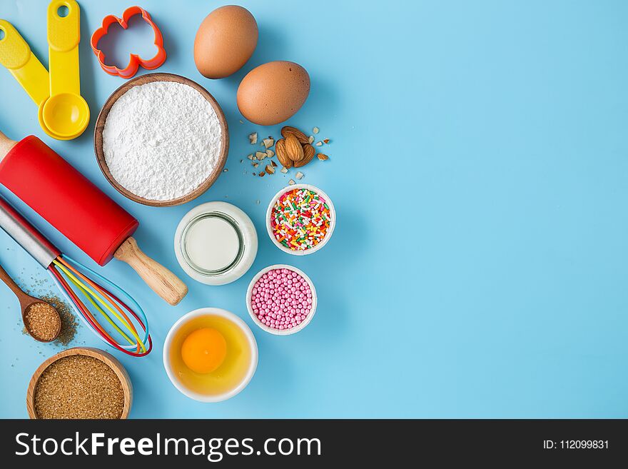 Baking background with ingredients eggs, flour, milk, sugar and cake decor on light blue table. Baking background with ingredients eggs, flour, milk, sugar and cake decor on light blue table