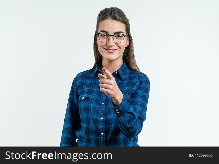 Point your finger at you, young beautiful cute cheerful girl smiling looking at camera over white background