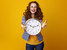 Smiling Woman On Yellow Background With Clock Showing Thumbs Up Royalty Free Stock Photo