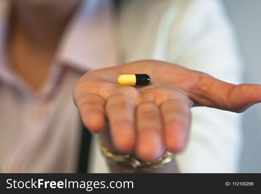 Focus of a small medicine capsule on a hand