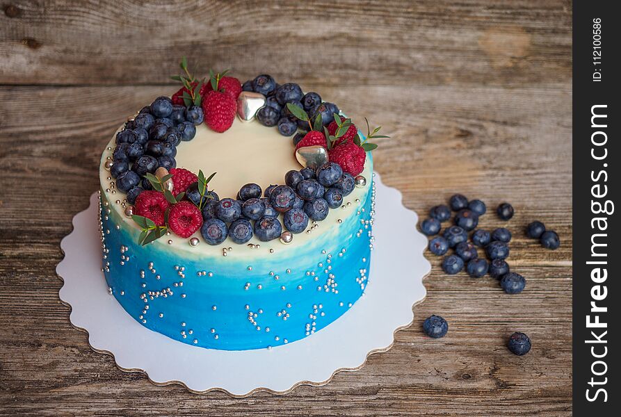 Home made pale blue cake with raspberry and blueberry on wooden table. Home made pale blue cake with raspberry and blueberry on wooden table