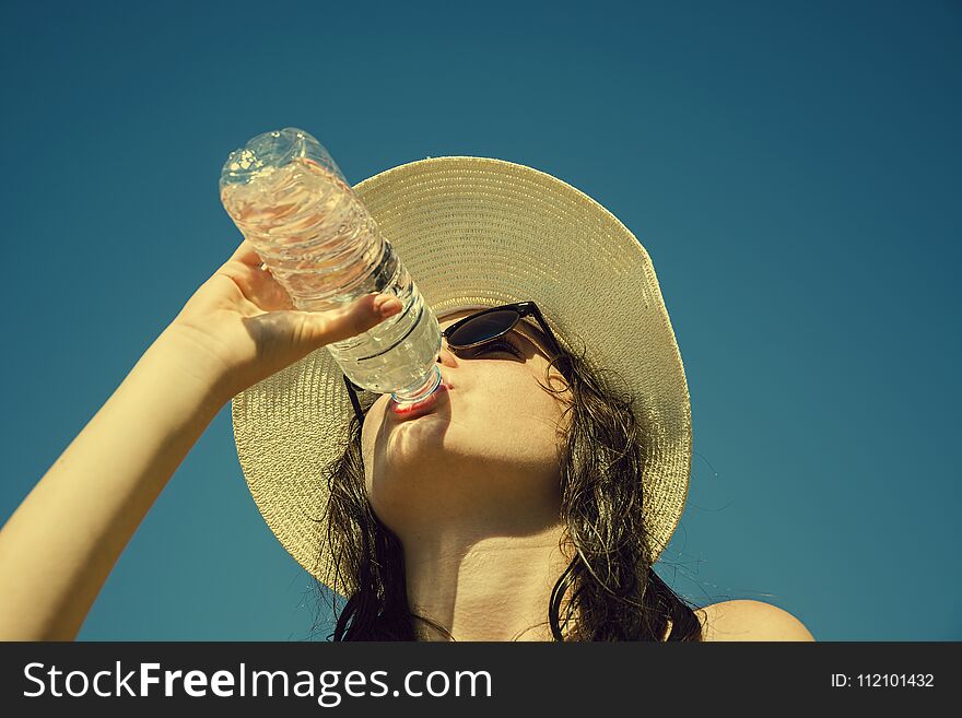 Young Girl Is Drinking Water On The Blue Sky Background.