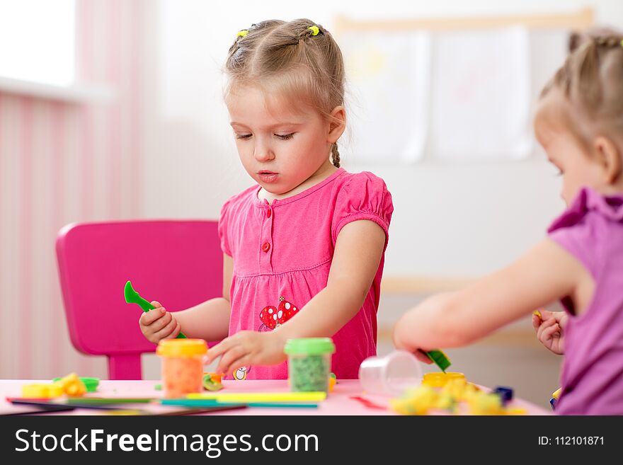 Children creativity. Kids sculpts from clay. Cute little girl moulds from plasticine on table in nursery