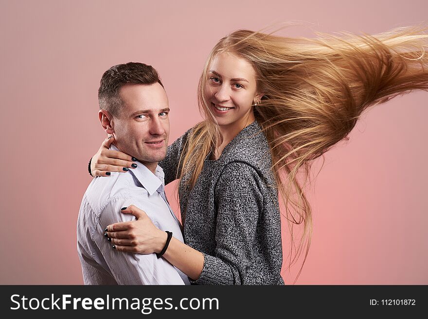 Happy smiling caucasian couple hugging isolated on pink background