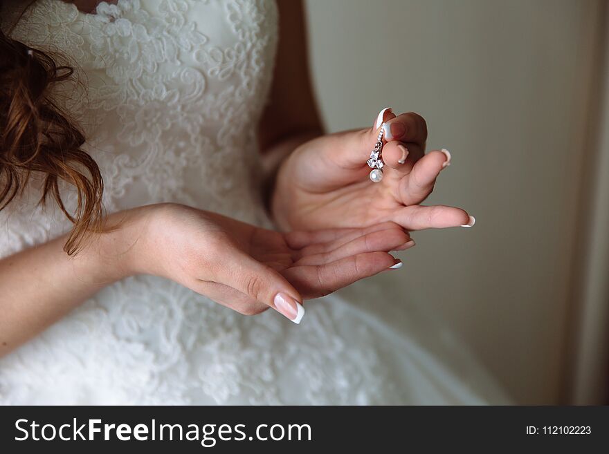 Earrind in the hands of the bride on black background. Concept of jewelry.