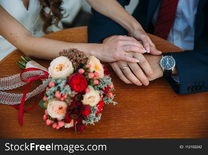 Closeup groom and bride are holding hands at wedding day and show rings. Concept of love family.