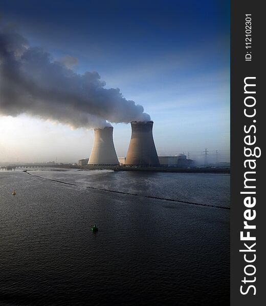 Two big funnels and smoke coming out of them. Nuclear plant in West Europe. Blue sky in the background. Two big funnels and smoke coming out of them. Nuclear plant in West Europe. Blue sky in the background.