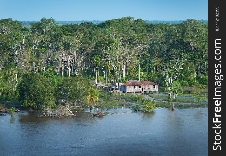 Detail from Amazon river, small wooden house in the jungle. Blue sky in the background. Detail from Amazon river, small wooden house in the jungle. Blue sky in the background.