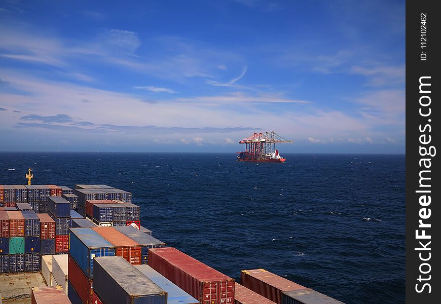 Big container vessel passing special crane transport vessel