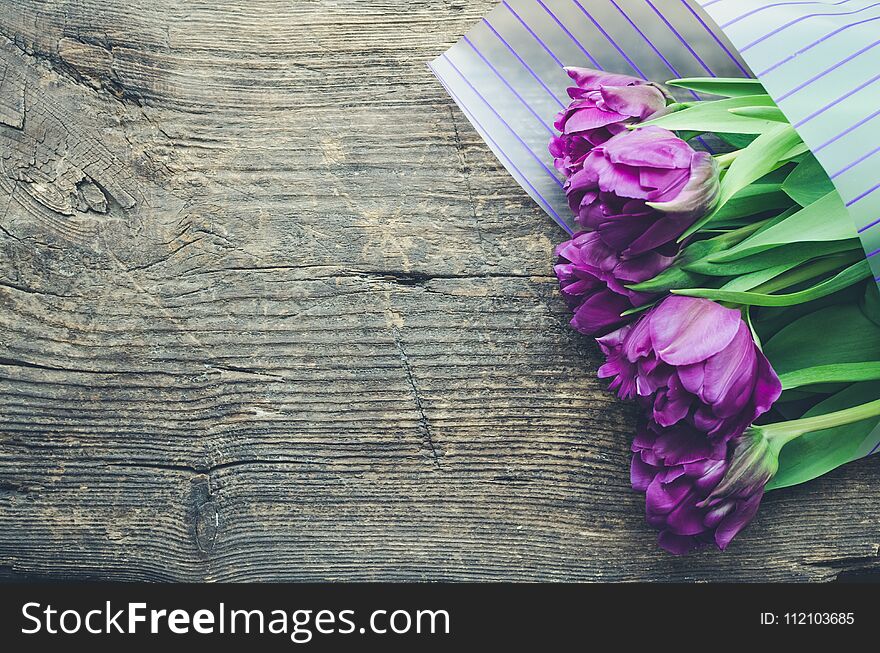 Bouquet of purple tulips on old wooden background. Valentines, Mothers, Womens Day and greeting concept. View from above with copy space. Banner template layout mockup for post blog social media.