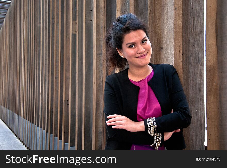 Business woman stands with big smile and with Thai silk dress and formal suit stands in front of wooden wall. Business woman stands with big smile and with Thai silk dress and formal suit stands in front of wooden wall.