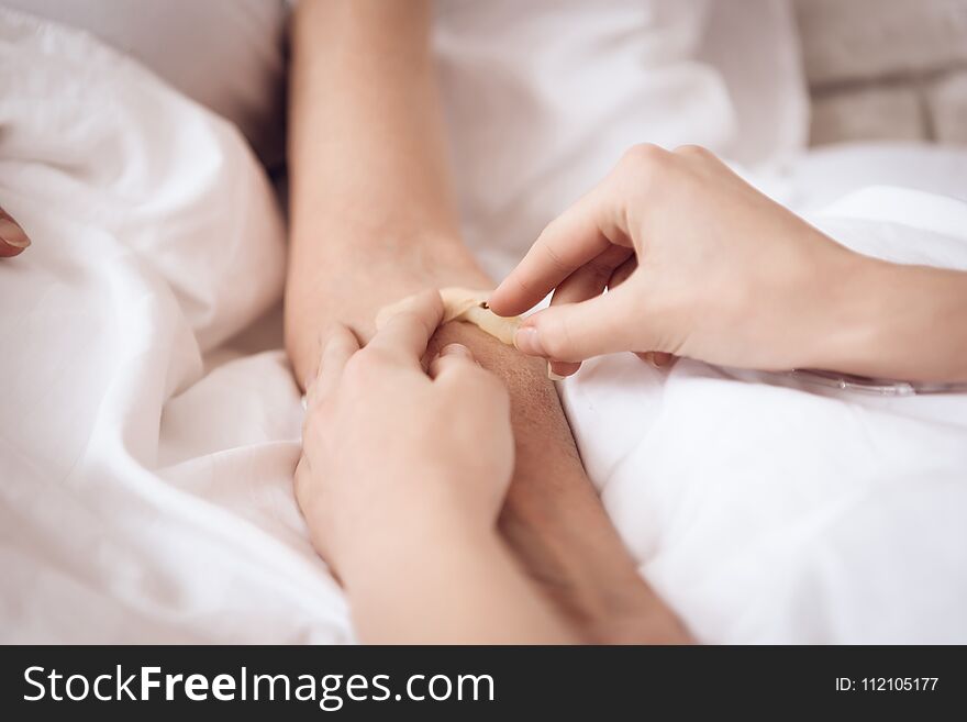 Close up. Girl is nursing elderly woman at home. Girl is putting drop counter needle.