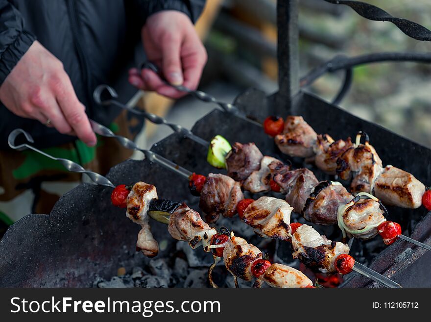 Male hand with shish kebab skewers on the grill close up