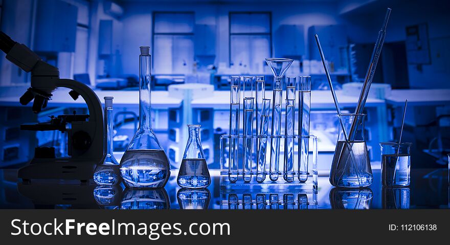 Microscope and laboratory glassware composition in laboratory. Blue background. Place fort text. Microscope and laboratory glassware composition in laboratory. Blue background. Place fort text.