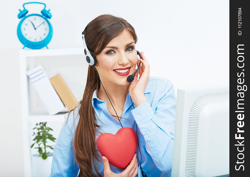 Portrait of call center smiling operator with phone headset isolated on white office background hold red heart. Help concept.