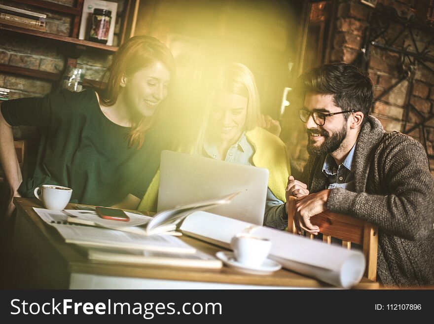 Three young student using laptop together and talking. Small group people. Three young student using laptop together and talking. Small group people.