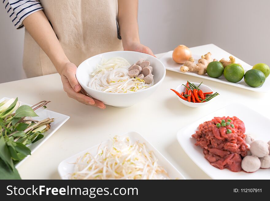 Female chef prepare traditional Vietnamese soup Pho bo with herb