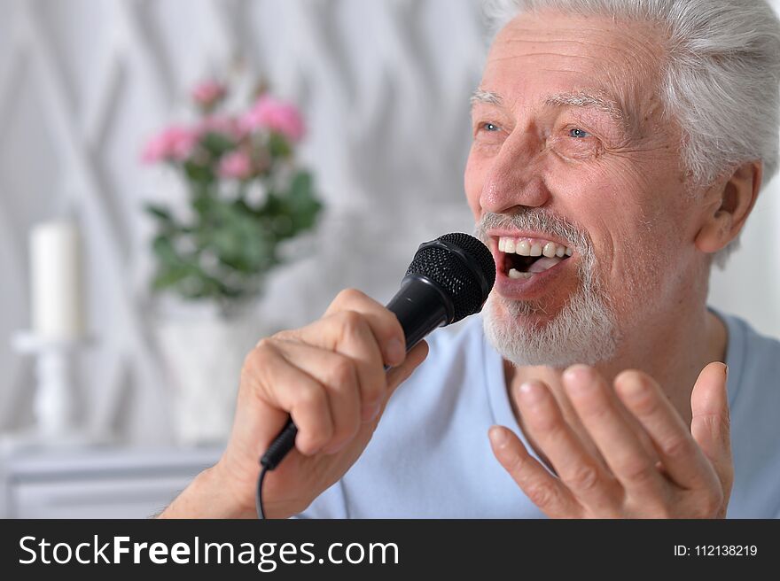 Portrait of excited senior man holding microphone