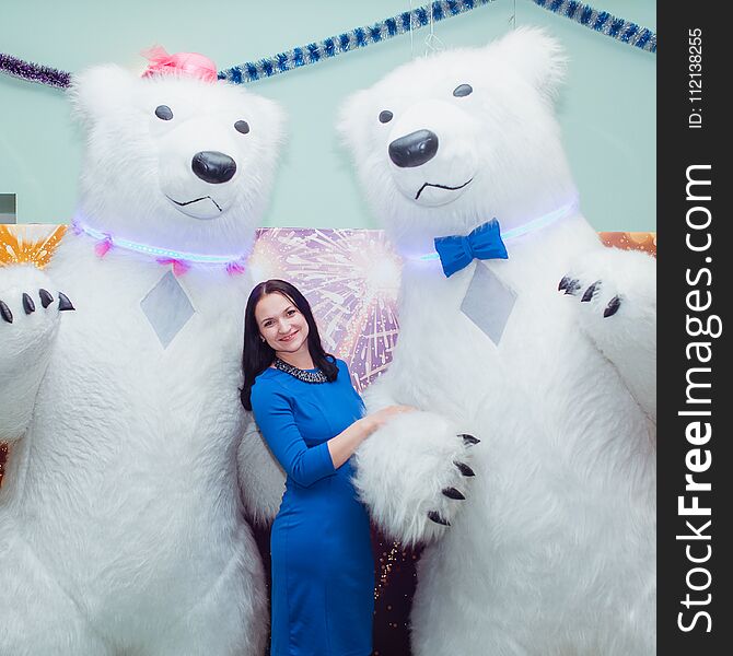 Young beautiful girl at the party is photographed with the big bears