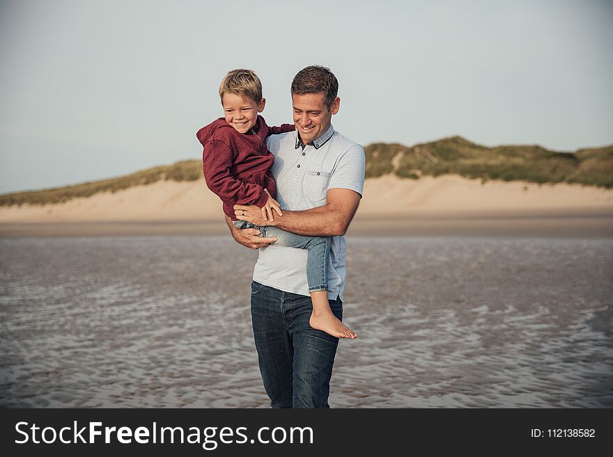 Father and son spending some time together, walking down the beach on holiday. Father and son spending some time together, walking down the beach on holiday.