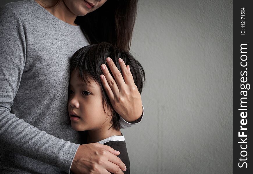 Sad little boy being hugged by his mother at home.