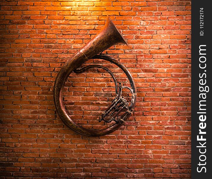 Old French horn on brick wall background.