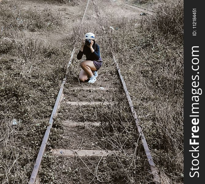 Woman White Round Hat Holding Black Dslr Camera on Rail Way