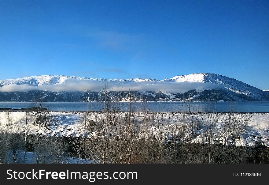 Landscape Photo of Body of Water Within Snow Coated Mountain Range