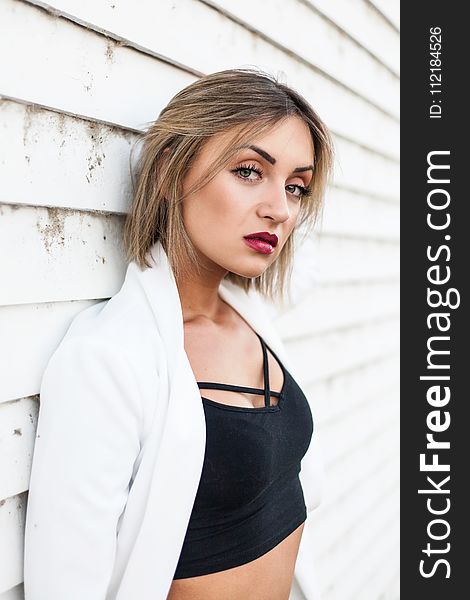 Woman Wearing Black Crop Top Leaning Against White Wall