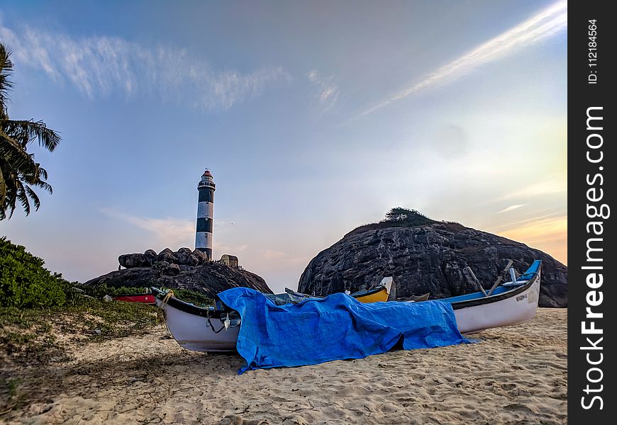 White Canoe With Blue Cover On Sand