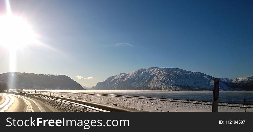 Landscape Photo of Gray Road Across Two Gray Land Formations