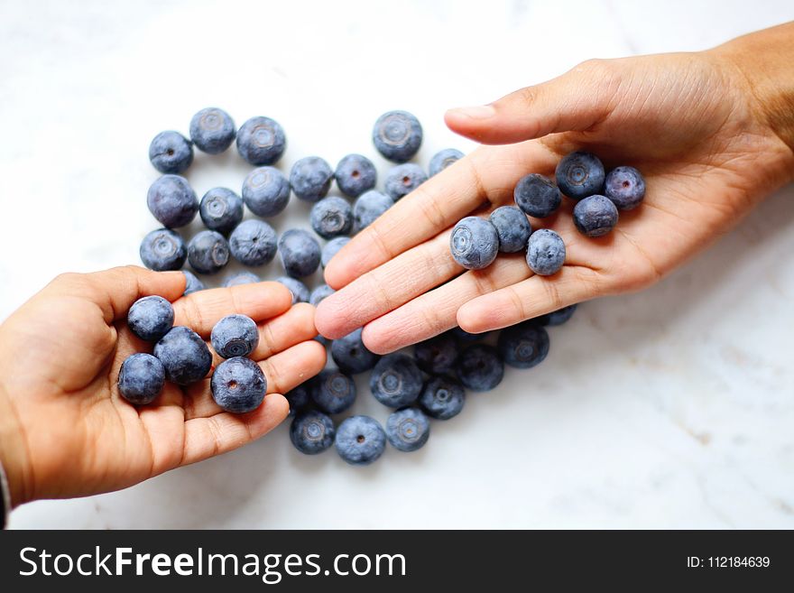 Two Person&x27;s Hand With Blueberries On Top