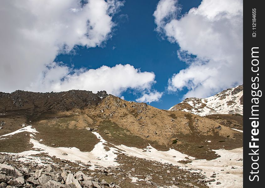 Snow Covered Hill Under Cloudy Sky At Daytime