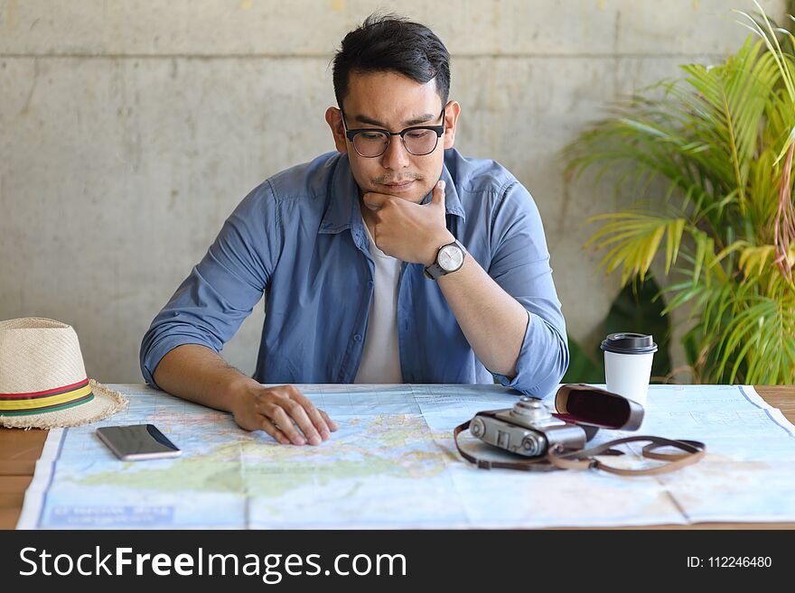 Asian tourist looking at worldmap and plans for his new trip