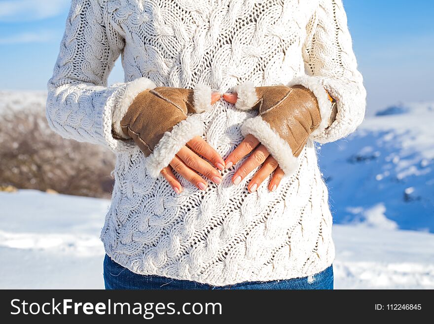 Close up woman showing heart sigmn on baby bump on a sunny winter day - maternity concept. Close up woman showing heart sigmn on baby bump on a sunny winter day - maternity concept