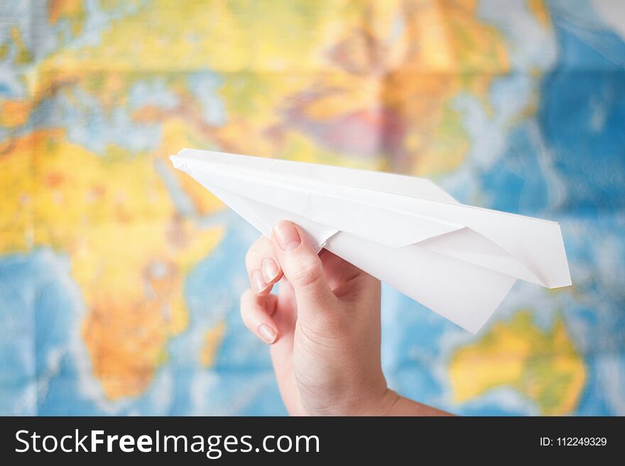 Paper airplane in hand on world map background