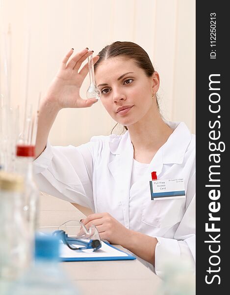 Woman lab assistant holding a empty test tube and watch closely on it