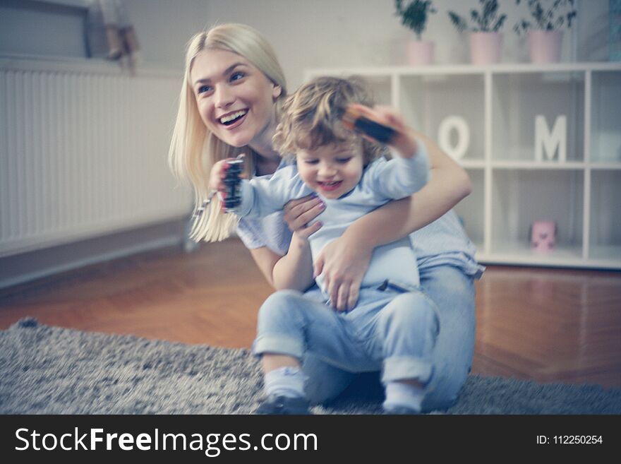 Young mother playing with son at home and sitting on floor. Young mother playing with son at home and sitting on floor.