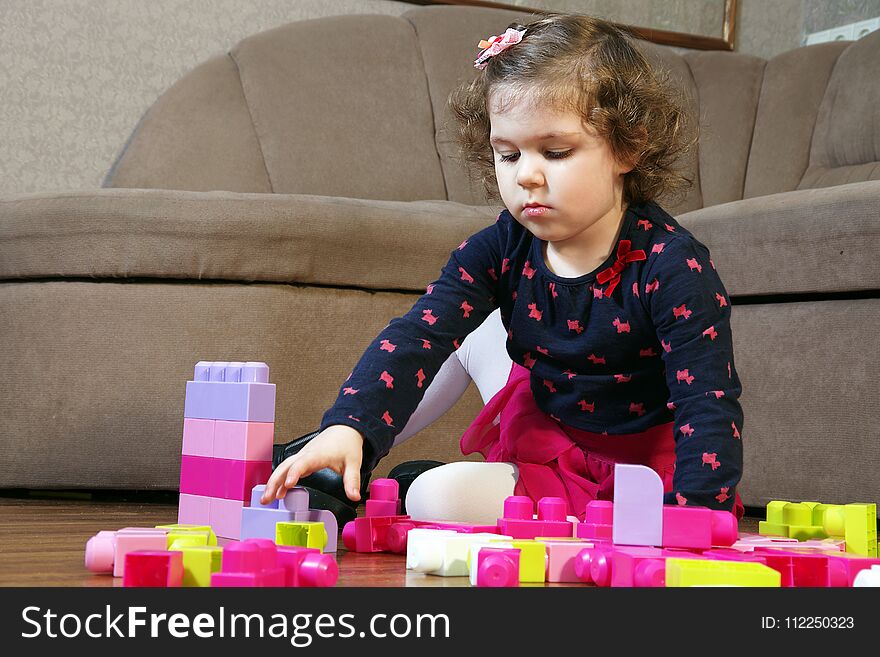 A little girl builds colorful plastic cubes. A little girl builds colorful plastic cubes