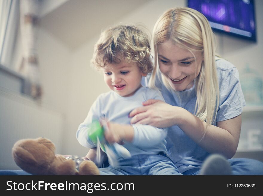 Young Mom playing with baby son in their living room. Close up.