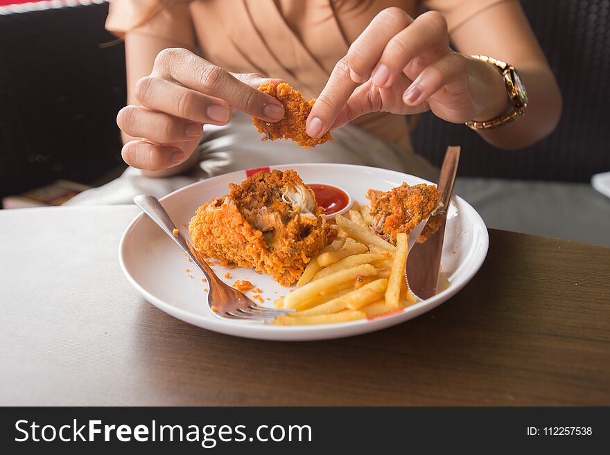 Fried chicken in young woman hand select focus, Hand with fried chicken blur background, Close-up Fried chicken