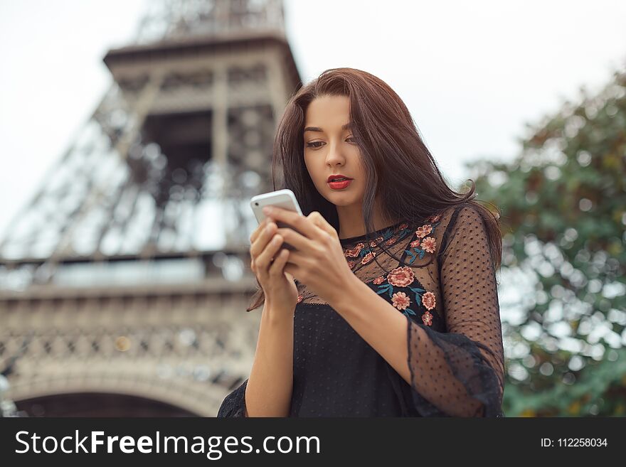 Travel woman using smartphone near the Eiffel tower and carousel, Paris.