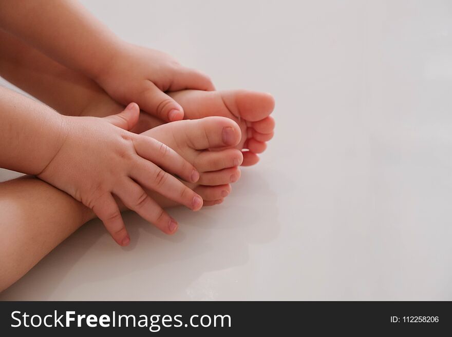 Close-up Baby Grabbed His Legs With His Hands. Concept Of Children`s Yoga, Gymnastics For Children, White Background