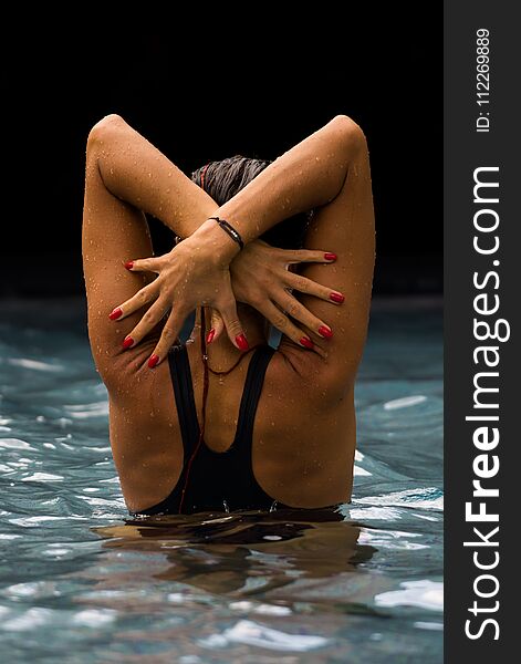 Young beautiful woman making water splash at the pool